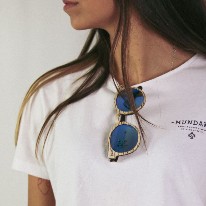 Detalle de las Gafas ERIKA SAVAGE colgadas del cuello de una camiseta  blanca que viste nuestra modelo